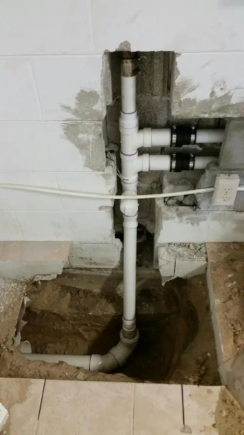everydayplumber-drain-sewer-line-repair Exposed PVC drain and sewer line repair in concrete foundation with new piping installed to replace damaged section