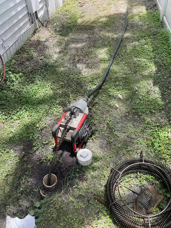 plumber-drain-cleaning-sewer-machine Professional drain cleaning machine snaking a sewer line through an outdoor cleanout to remove blockages and restore proper flow